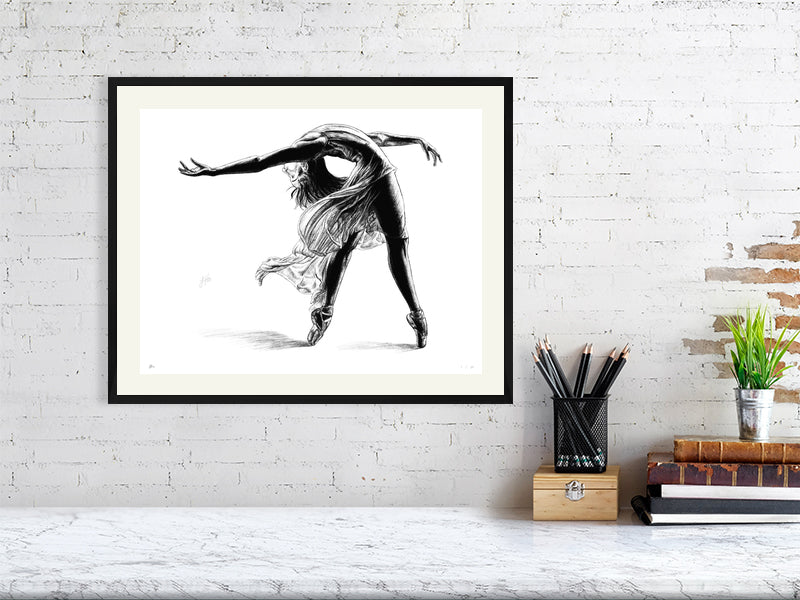Large framed pencil drawing of a ballet dancer mid pose, by Sophie Hall. Print hangs on a white brick wall.