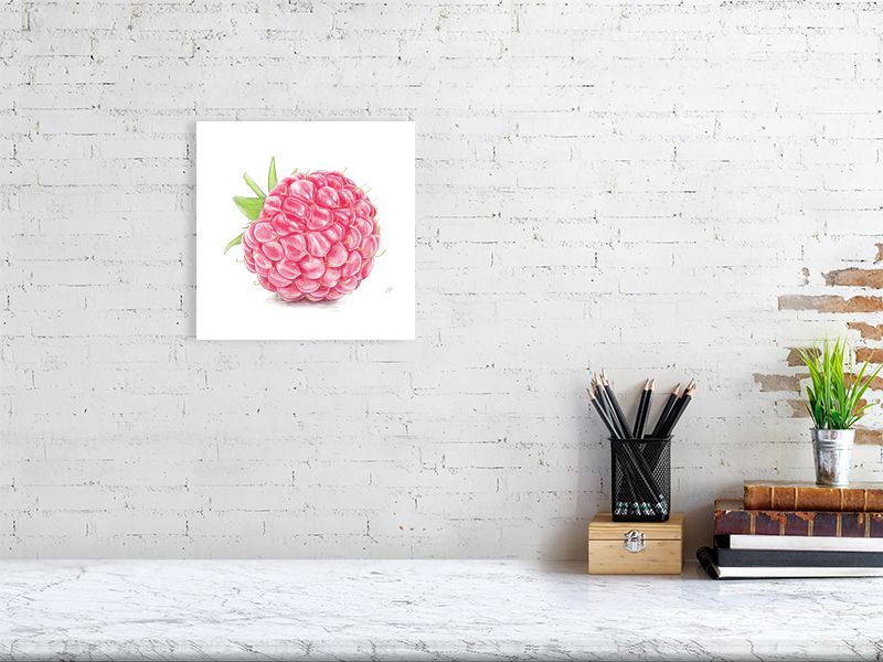 A medium size unframed still life hanging on a white brick wall over a desk. Artwork is a detailed red and green pencil drawing of a raspberry, showcasing realistic highlights on each segment.