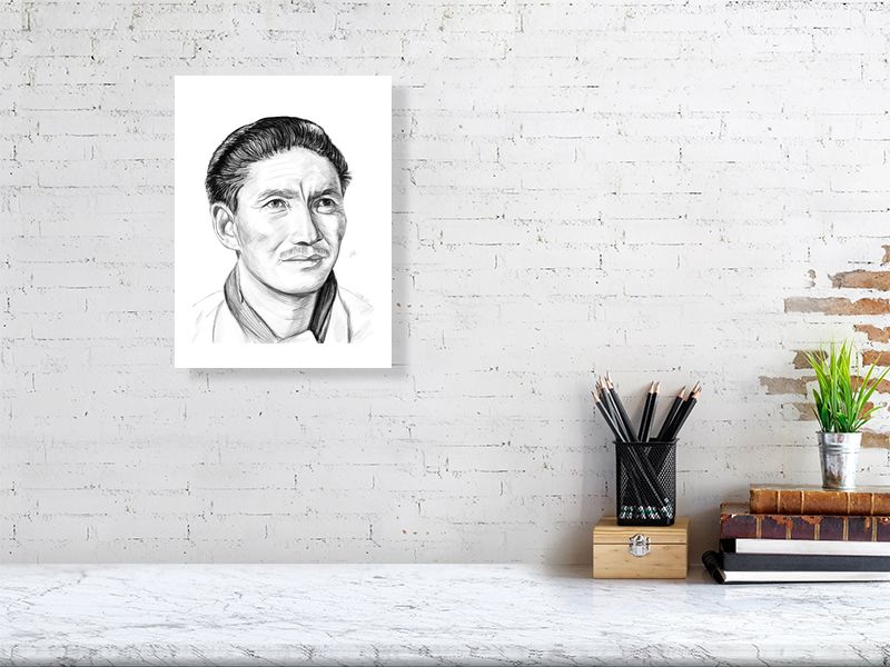 A medium unframed pencil drawing portrait of Tenzing Norgay, a legendary explorer known for climbing Everest, hanging on a white brick wall over a desk.