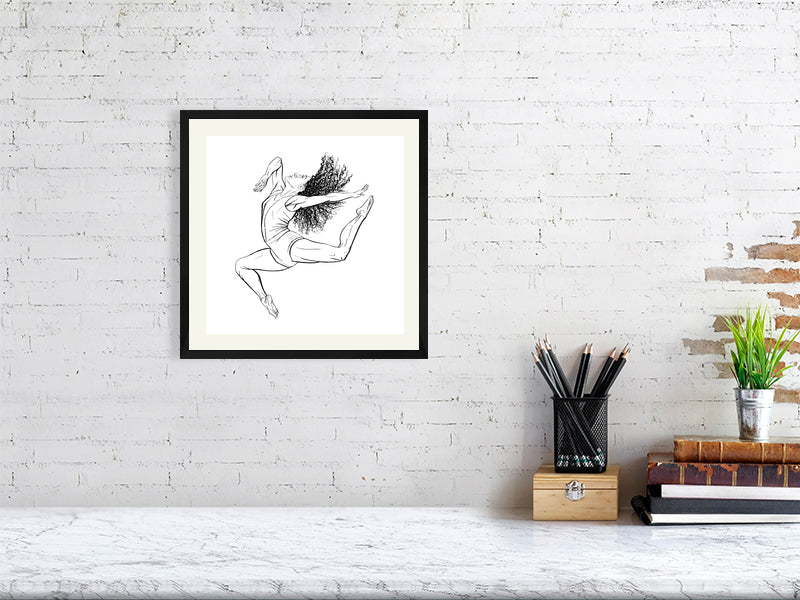 A medium sized square framed ink drawing of a ballet dancer in mid-leap, signed by Sophie Hall and hanging on a white brick wall over a marble desk.