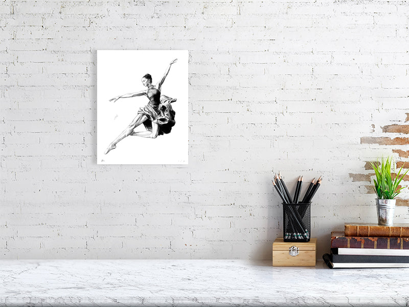A small unframed pencil drawing of a ballet dancer in mid-jump, hanging on a white brick wall.