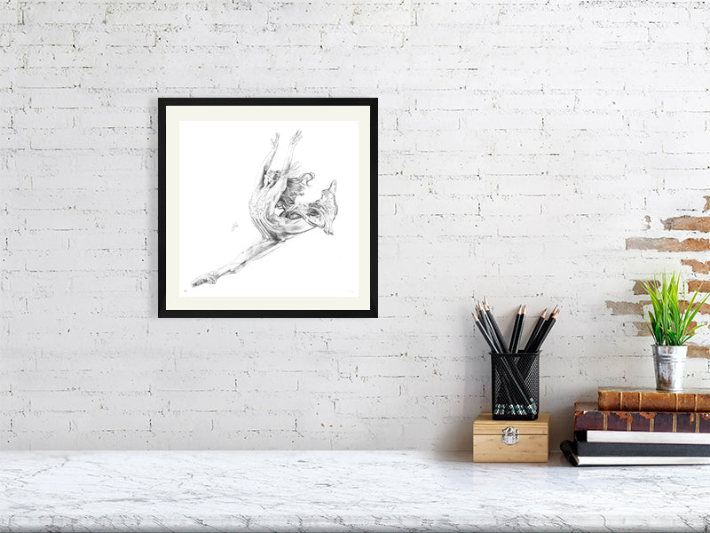 Medium size framed pencil drawing of a ballet dancer in a dynamic pose, inspired by Stravinsky's Firebird ballet. Hanging on a white brick wall above a marble desk.