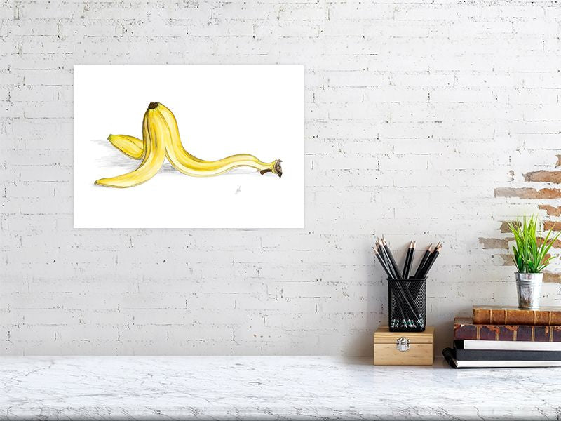 A large unframed watercolour and pencil illustration of a banana peel with a focus on realistic texture and colour, hanging on a white brick wall above a desk.