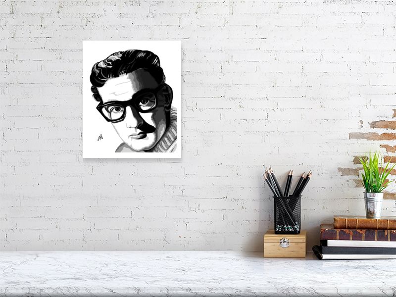 A medium size unframed ink portrait of Buddy Holly in sharp contrast monochrome, hanging on a white brick wall over a desk.