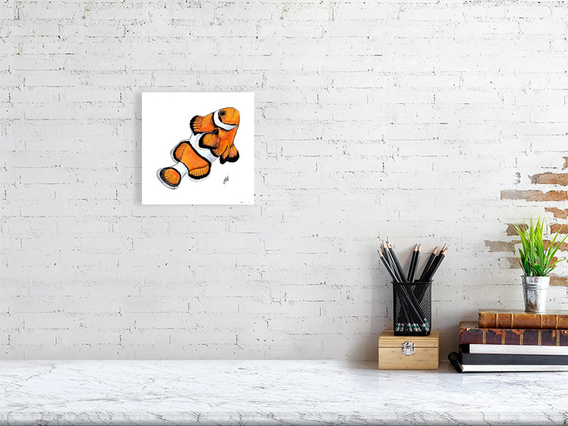Small unframed ink and watercolour artwork of a bright orange and white  clownfish, hanging on a white brick wall above a desk.