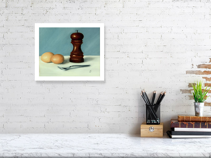 A small unframed print of a still life oil painting featuring a wooden salt cellar, two eggs, and a spoon on a white surface, against a blue background, signed by the artist and hanging on a white brick wall.