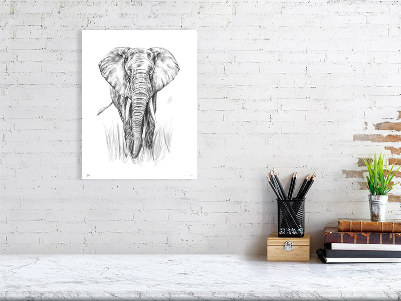 A large unframed detailed pencil drawing of an elephant hanging on a white brick wall over a desk.
