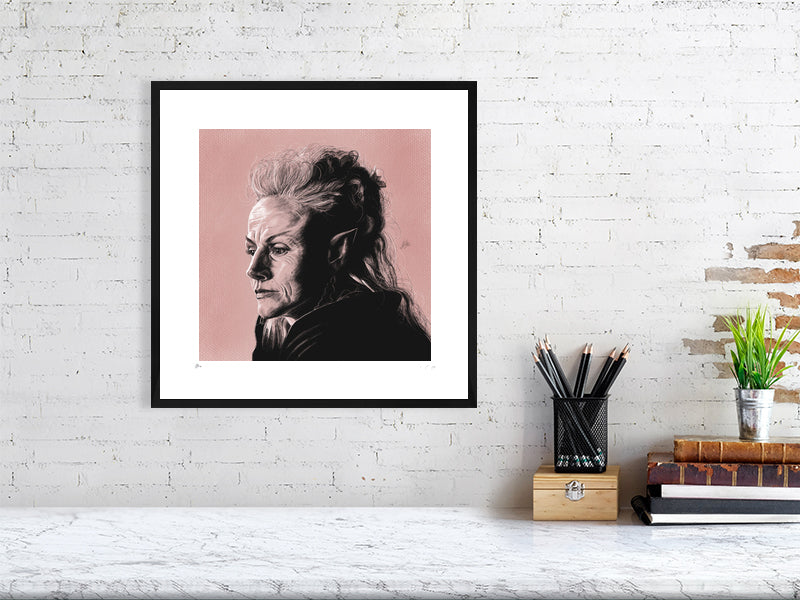A large framed pencil and chalk portrait of Maxine Peake as Titania, on a pink pastel textured background. Hanging in a black frame with a white mount on a white brick wall over a desk.