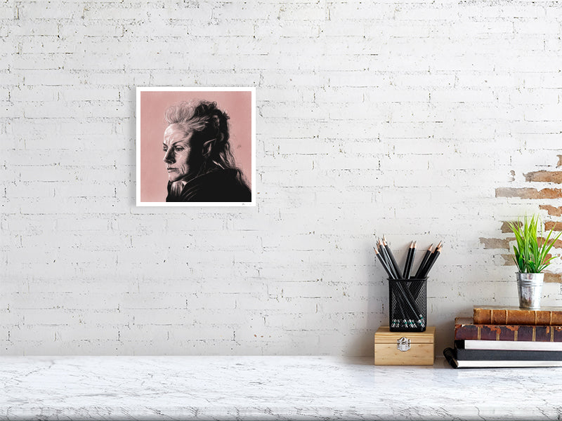A small unframed pencil and chalk portrait of Maxine Peake as Titania, on a pink pastel textured background. Hanging on a white brick wall over a desk.