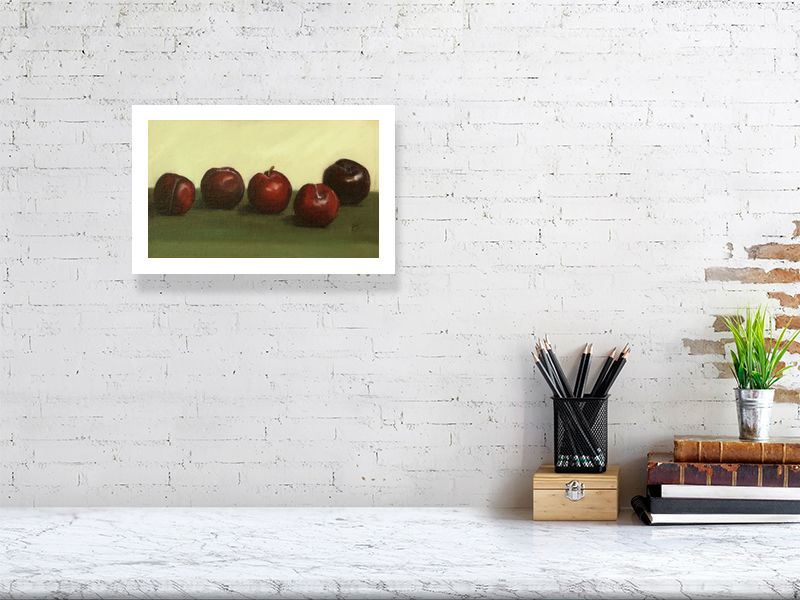 A small giclee print oil painting still life of five ripe plums on a deep green cloth, signed by Sophie Hall and hanging on a white wall above a desk.