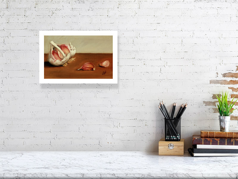 A small unframed print of a traditional still life oil painting featuring garlic bulbs and cloves on a wooden surface, signed by the artist, Sophie Hall and hanging on a white wall over a marble desk.