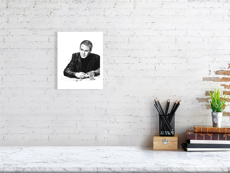 An unframed pencil portrait of George Clooney as Danny Ocean from Ocean's Eleven, drawn in black and white, hanging on a white brick wall over a desk.