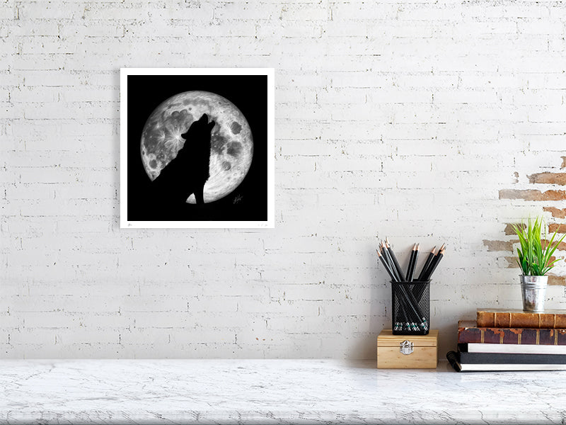 A medium unframed pencil drawing of a wolf howling at the moon, with the outline of the wolf silhouetted by the a large full moon behind, on a black background. Hanging on a white brick wall over a desk.