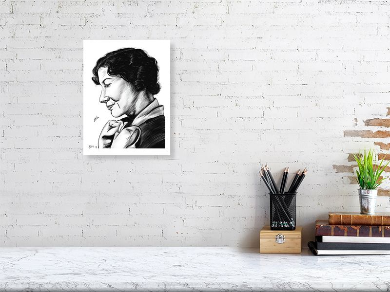 A medium, unframed black and white ink drawing of a woman with her head slightly tilted, looking off to the side, hanging on a white brick wall above a desk.