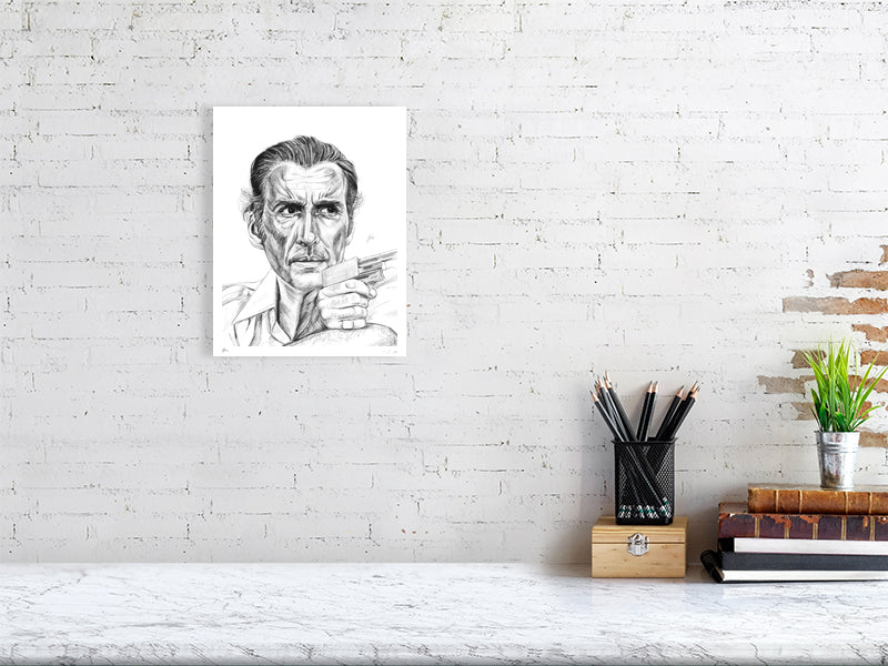 A small unframed pencil drawing of Christopher Lee as Antonin Scaramanga from The Man with the Golden Gun. Signed by Sophie Hall and hanging on a white brick wall over a desk.