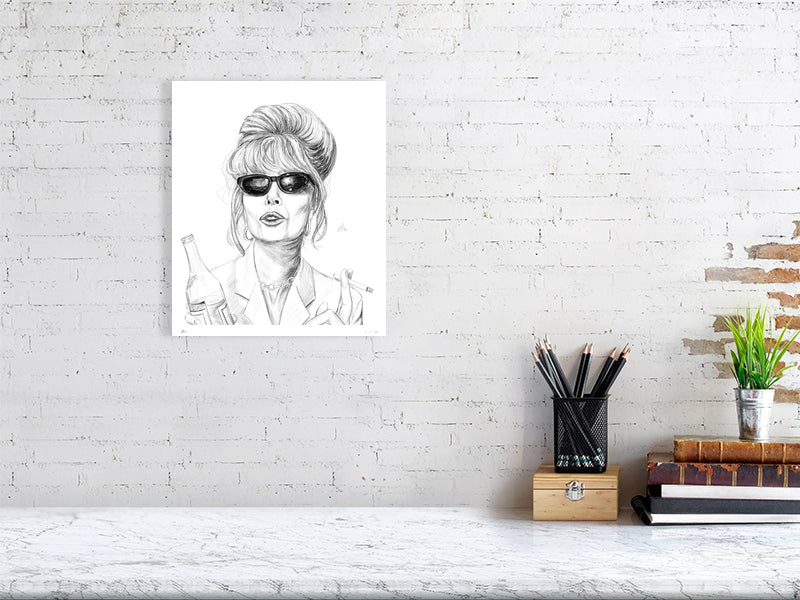 A medium size unframed pencil drawing of Patsy from the British comedy series Absolutely Fabulous, signed by Sophie Hall and hanging on a white brick wall over a desk.
