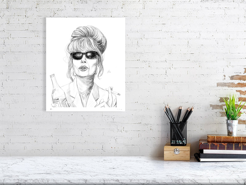 A large unframed pencil drawing of Patsy from the British comedy series Absolutely Fabulous, signed by Sophie Hall and hanging on a white brick wall over a desk.