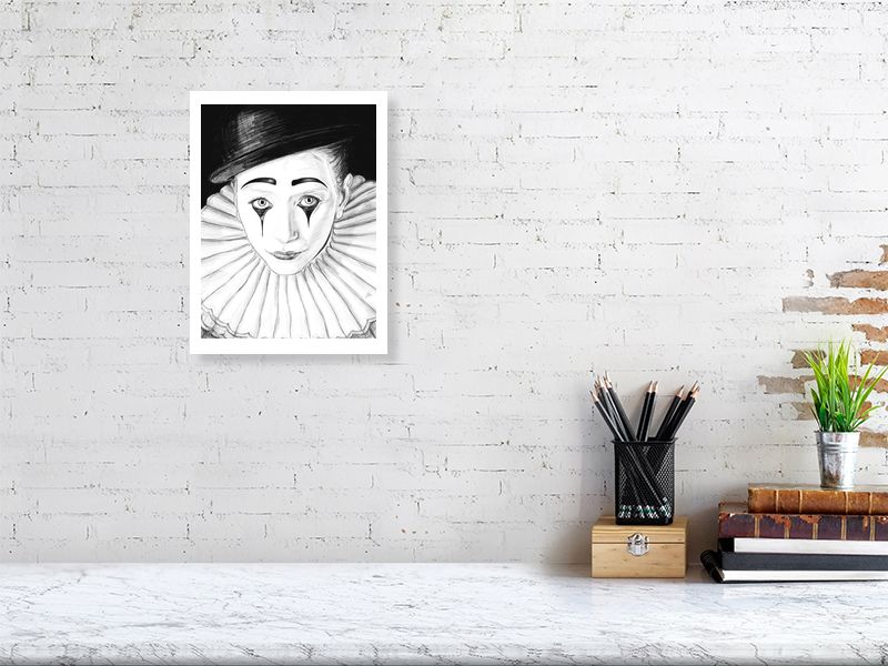 An unframed pencil drawing of a sad Pierrot clown with white face paint, black hat, and large white collar. Picture hangs on a white brick wall over a desk.