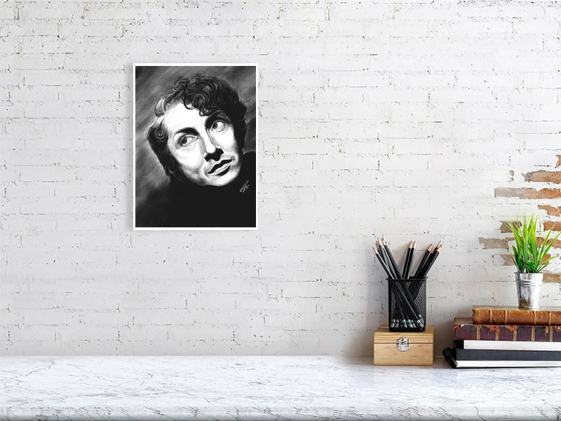 A medium unframed black and white pencil drawing of Quentin Crisp, featuring expressive facial features and a direct gaze. Hanging on a white brick wall over a desk.