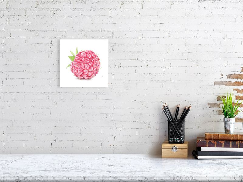 A small unframed drawing hanging on a white brick wall over a desk. Artwork is a detailed red and green pencil drawing of a raspberry, showcasing realistic highlights on each segment. 