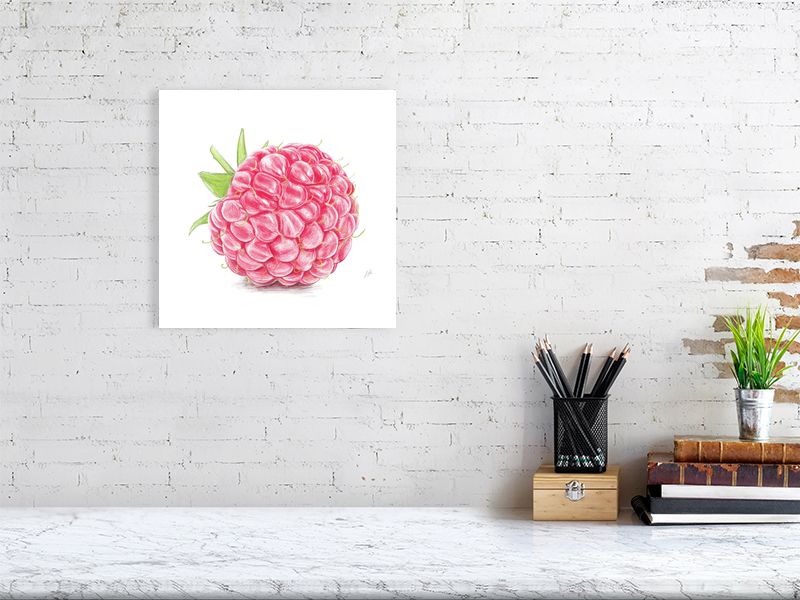 A large unframed still life hanging on a white brick wall over a desk. Artwork is a detailed red and green pencil drawing of a raspberry, showcasing realistic highlights on each segment. 