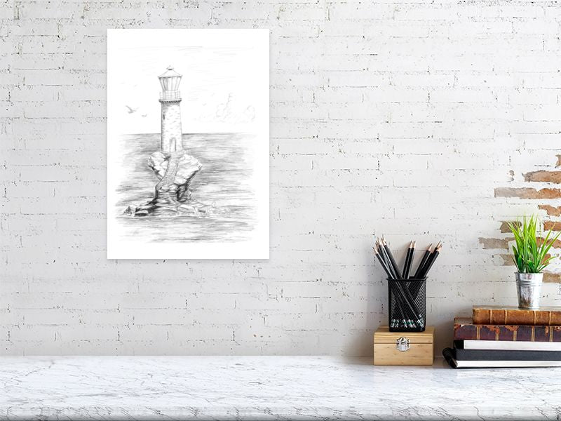 A large unframed pencil drawing of a lighthouse standing on a remote eroded rock in the middle of the sea. Signed by Sophie Hall and hanging on a white brick wall above a desk.