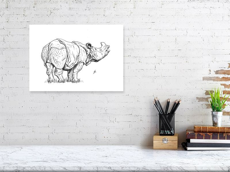 A large unframed contemporary ink drawing of a rhinoceros. Monogram signed by Sophie Hall and hanging on a white brick wall above a desk.