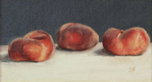 A traditional still life oil painting of three flat peaches on a white piece of linen, signed by Sophie Hall.