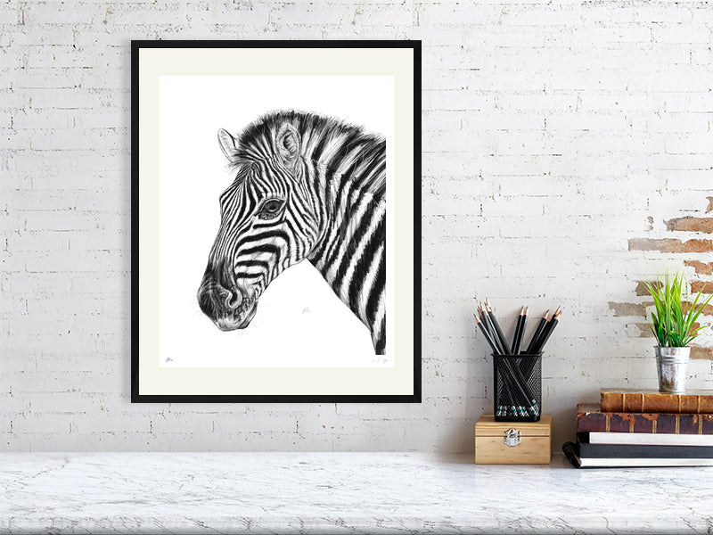 A large framed pencil drawing of a zebra, hanging on an white brick wall over a marble desk. Signed and numbered by the artist.